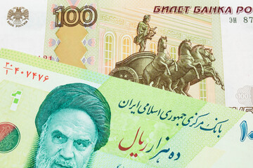 A macro image of a Russian one hundred ruble note paired up with a blue and green ten thousand rial bank note from Iran.  Shot close up in macro.