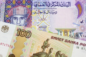 A macro image of a Russian one hundred ruble note paired up with a colorful one rial note note from Oman.  Shot close up in macro.