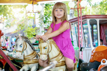 Beautiful little girl on a retro carousel ride