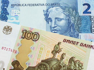 A macro image of a Russian one hundred ruble note paired up with a blue two real bank note from Brazil.  Shot close up in macro.