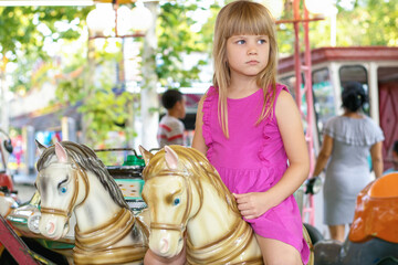 Beautiful little girl on a retro carousel ride
