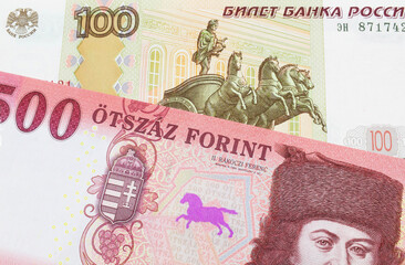 A macro image of a Russian one hundred ruble note paired up with a red and white five hundred forint note from Hungary.  Shot close up in macro.