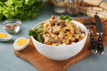 Salad with ham, eggs, onion and mushrooms in a white bowl on a wooden board, Horizontal format, Closeup