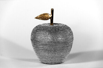 Rhinestone-studded apple decoration with gold stem and leaf. High key composition. Modern, elegant home decor.