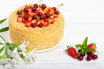 Beautiful napoleon cake with strawberries and cherries mixed with i mint on a light background