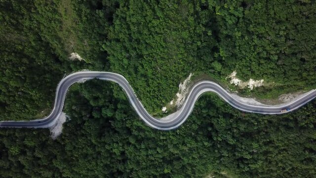 Mountain winding zig zag road. Top aerial view: cars driving on road from above.