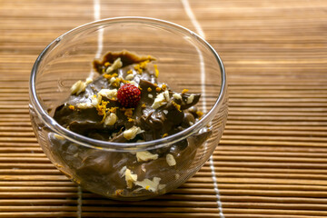 Two glasses of homemade avocado chocolate and walnut mousse decorated with strawberry, on wooden background. Home cooking, vegetarian food, healthy lifestyle. Paleo diet, detox