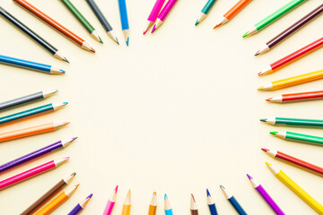 Blank notepad surrounded by multicolored pencils. Top view..