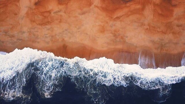 Flying over a sandy beach. Waves break on a sandy beach on the Atlantic coast, aerial View. Nazare, Portugal.