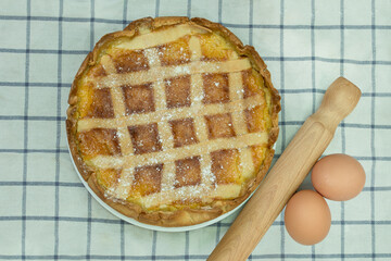 Close up to a napolitan pastiera, tipical easter sweet, with eggs and rolling pin.