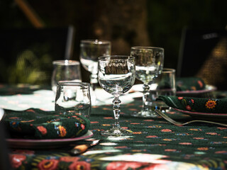 A simple but elegant tablecloth and cutlery laid out on it. Crystal glasses in the sun. Everything is ready for lunch in the garden.