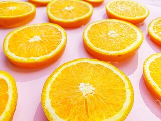 Slices of juicy orange oranges on a bright pink background.