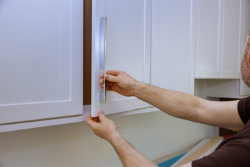 Worker install new handle on the white cabinet