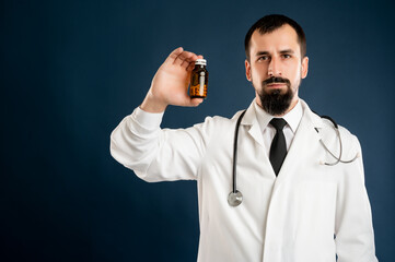Male doctor with stethoscope in medical uniform holding dose of pills