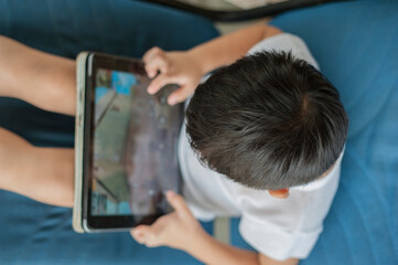 Penang, Malaysia - January 14, 2020 : Little kid's using digital touchscreen phone tablet computer playing games.