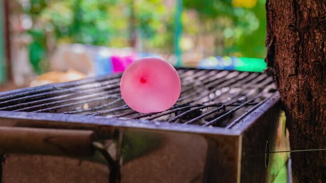 Cinemagraph of smoke emitted from a hot BBQ grill with a water balloon placed on it. Close up, loop with selective focus.