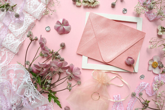 wedding card design. bouquet of flowers, wedding ring, white lace and envelope on a pink background