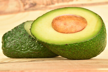 Green fresh ripe tasty avocado, close-up, on a background of natural wood.