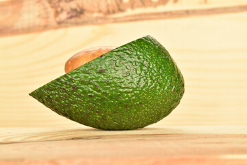 Green fresh ripe tasty avocado, close-up, on a background of natural wood.