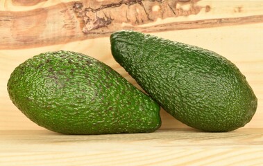 Green fresh ripe tasty avocado, close-up, on a background of natural wood.