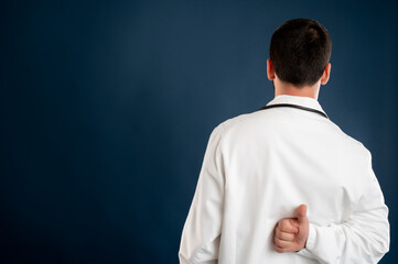 Male doctor with stethoscope in medical uniform showing thumbs up from behind