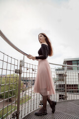 Woman standing on the rocky shore of the sea. Girl leaning on the railing. Looking away. Looking straight ahead. Rear view of a lonely young adult person. A beautiful seaside landscape. Blue sky.