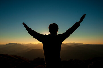 man on top of the mountain reaches for the sun. power, and victory concept. vacation and freedom concept