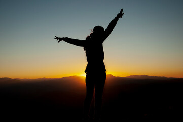 Woman, power, and victory concept.. Silhouette of Woman open arm under sunset. Silhouette of free woman enjoying freedom feeling happy at sunset. relaxing woman in pure happiness. 