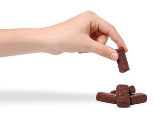 Child hand takes chocolate candy, isolated on white background. Hand holding chocolate candy over heap of candies .