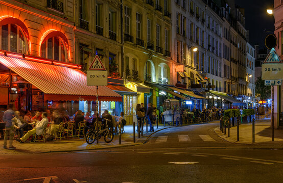 Night view of cozy street with tables of cafe in Paris, France