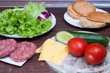 ingredients for making burgers. Cucumber, tomato, onion, lettuce, meat, sauce, sesame, buns