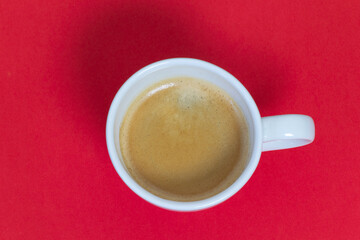 White cup of coffee from the zenith on red background