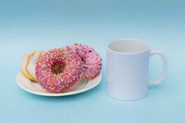 Absolutely white mug on a blue background. Nearby on a plate are three delicious, beautiful, seductive, high-calorie donuts. Unhealthy food. Breakfast concept. Romantic breakfast. Horizontal photo