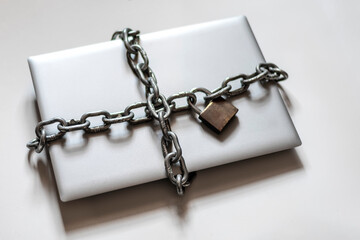 Laptop surrounded by chain with padlock for digital detoxification. Cenital plane.