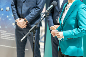 Business woman or female politician is giving a speech at media event - obrazy, fototapety, plakaty