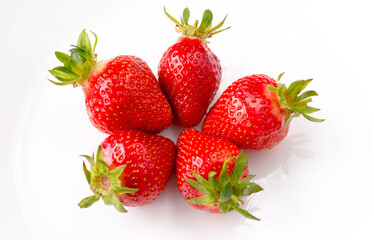 Ripe strawberries in the center of a white plate, on a white background