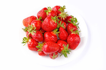 Ripe strawberries in the center of a white plate, on a white background