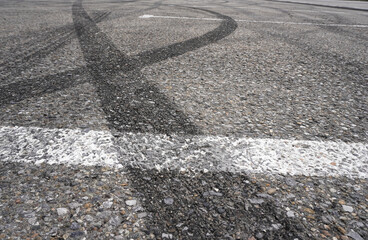 Asphalt texture with white line and tire marks.  Smooth asphalt road. Tarmac dark grey grainy road background.Top view