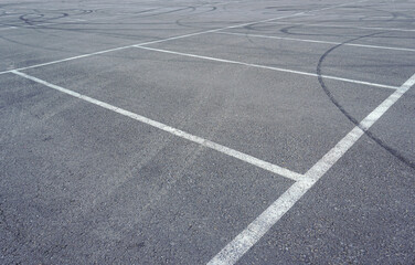 Fototapeta premium Asphalt texture with white line and tire marks. Smooth asphalt road. Tarmac dark grey grainy road background.Top view