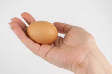 White and gray chicken eggs in a hand on a white background