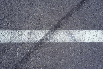 Asphalt texture with white line and tire marks.  Smooth asphalt road. Tarmac dark grey grainy road background.Top view