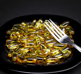 Vitamin pills over black dish. Supplement concept