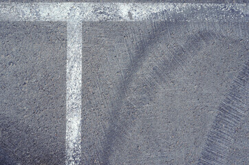 Fototapeta premium Asphalt texture with white line and tire marks. Smooth asphalt road. Tarmac dark grey grainy road background.Top view