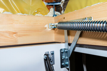 A spring tensioning mechanism that helps in opening a metal ladder to the attic placed in the ceiling of the house.
