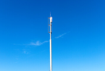 Obraz premium A mobile telecommunications tower or cell phone tower. The silhouette of the tower against the blue sky. The concept of telecommunications