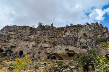 Fototapeta na wymiar Ancient rock-cut cave houses and christian temples cut in pink tufa stone, Ihlara Valley, Cappadocia, gorge,Turkey 