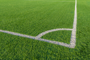 Obraz premium Green grass and white border lines on football ground. Soccer field on artificial turf. Artificial green grass texture. Artificial football field in an open stadium