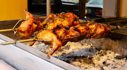 Rotisserie of the Lechon manok or roasted marinated chicken cooking over burning coals is popular Filipino street cuisine. 