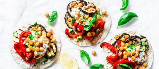 Fototapeta na wymiar Healthy vegetarian food banner. Grilled vegetables and spicy crunchy chickpeas tortillas on a light background, top view.Copy space