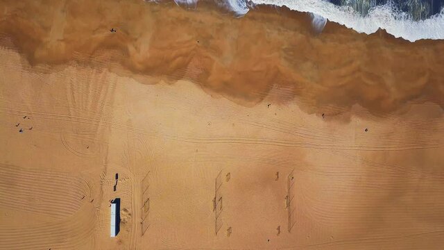 Flying over a sandy beach. Waves break on a sandy beach on the Atlantic coast, aerial View. Nazare, Portugal.